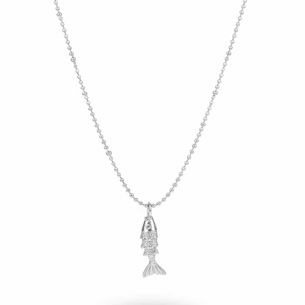 A silver fish pendant necklace on a delicate silver ball chain, shown against a plain white background with a soft shadow underneath.