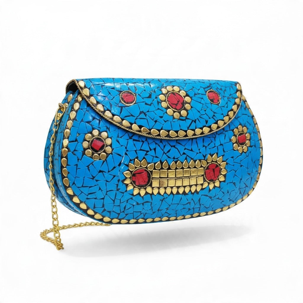 A bright blue mosaic handbag with gold-tone studs and red jewel accents, featuring a gold chain strap, photographed on a clean white background.